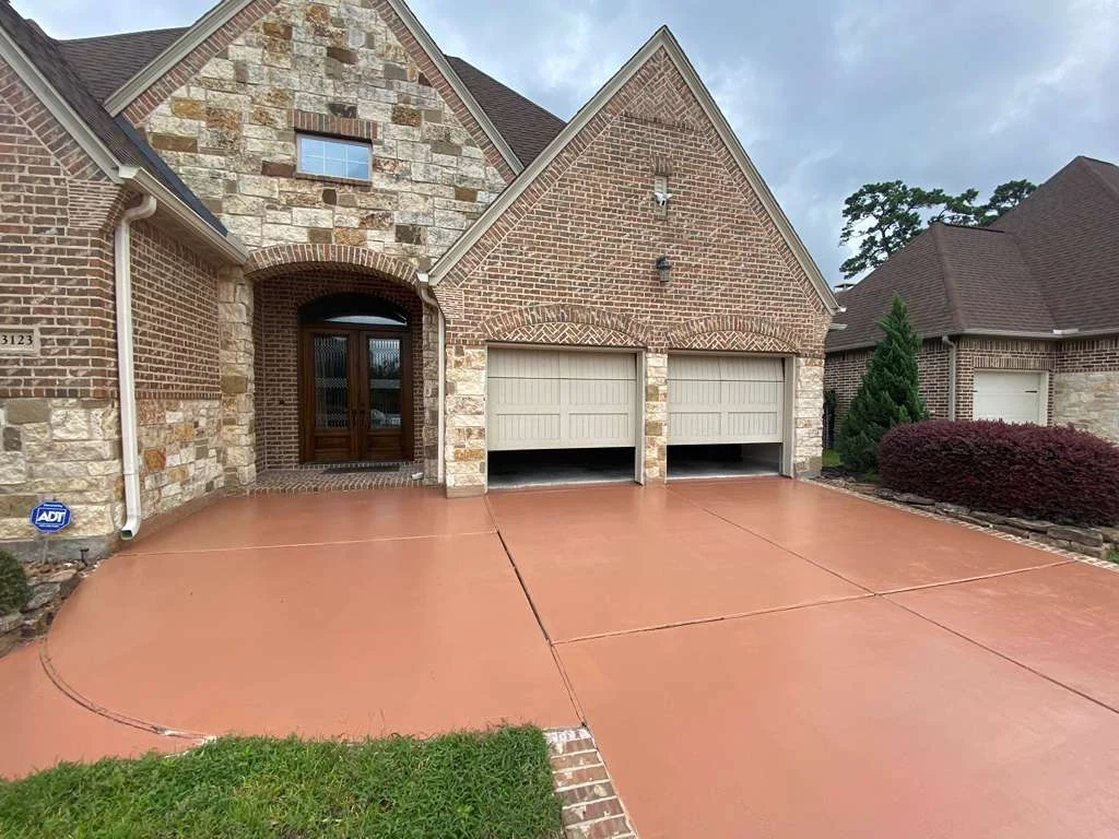 Warm-toned concrete driveway outside a brick home